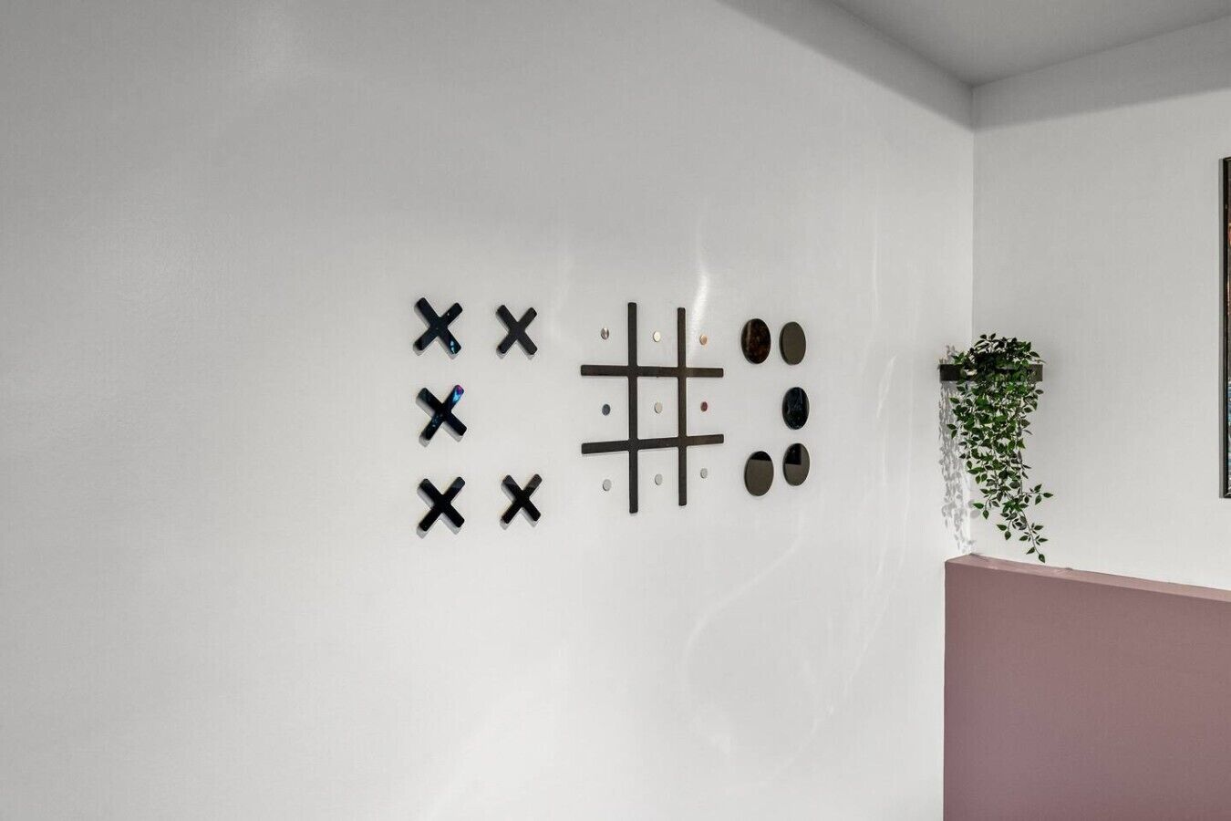 Pared con un diseño geométrico de formas negras y una pequeña planta en una maceta.