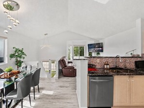 Una cocina moderna con comedor, horno empotrado y zona de estar con sofá.