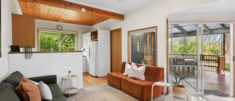 A modern living room with a sofa, a coffee table, and a rug. There is a sliding glass door leading to an outdoor deck.