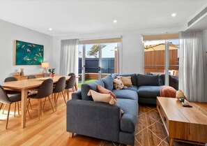 Un salon moderne avec un canapé d’angle, une table à manger et des chaises.