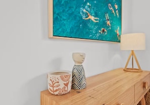 A wooden side table with a framed artwork, a lamp, and two decorative vases. - Driftwood – Luxury Coastal Townhouse in the Heart of Ocean Grove (Ocean Grove)