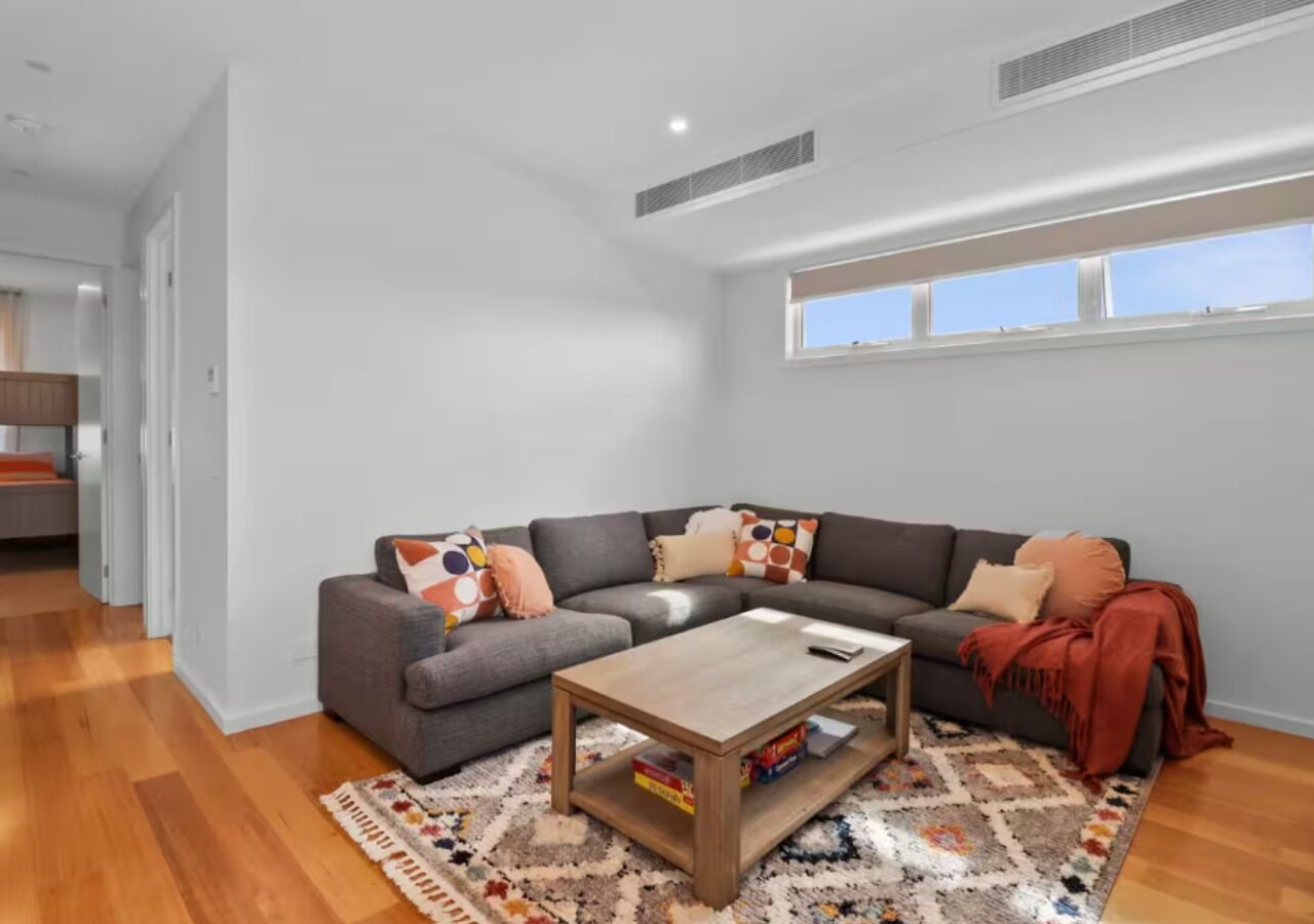 A modern living room with a grey sectional sofa, a wooden coffee table, and a patterned rug.