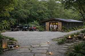 A rustic cabin with a gravel driveway, parked vehicles, and a fire pit. - Private 75-Acre Dome Estate: Waterfall, Farm, Trails & Pacific Views (Platanillo)