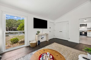 Ein modernes Wohnzimmer mit großem Fernseher, Kamin und Blick ins Freie.