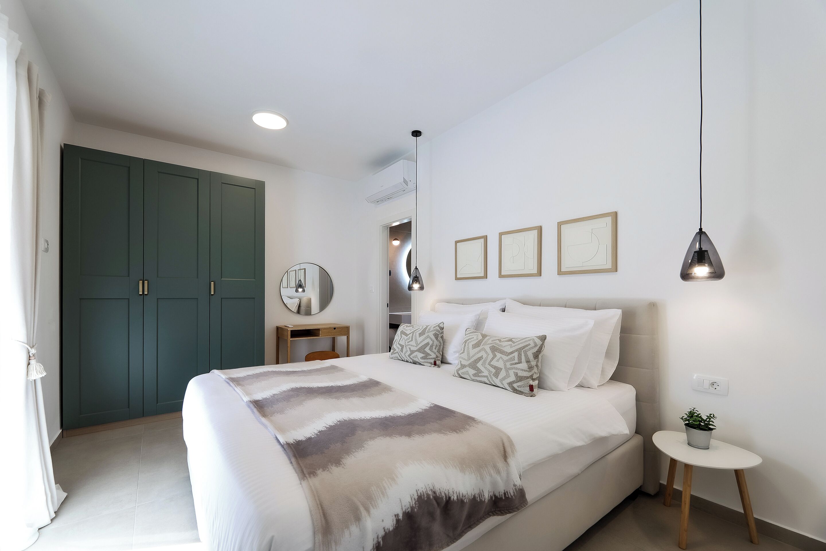 A bedroom with a bed, bedside table, lamp, and a small potted plant.