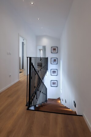 Ein modernes Interieur mit einer Holztreppe, weißen Wänden und gerahmten Bildern.