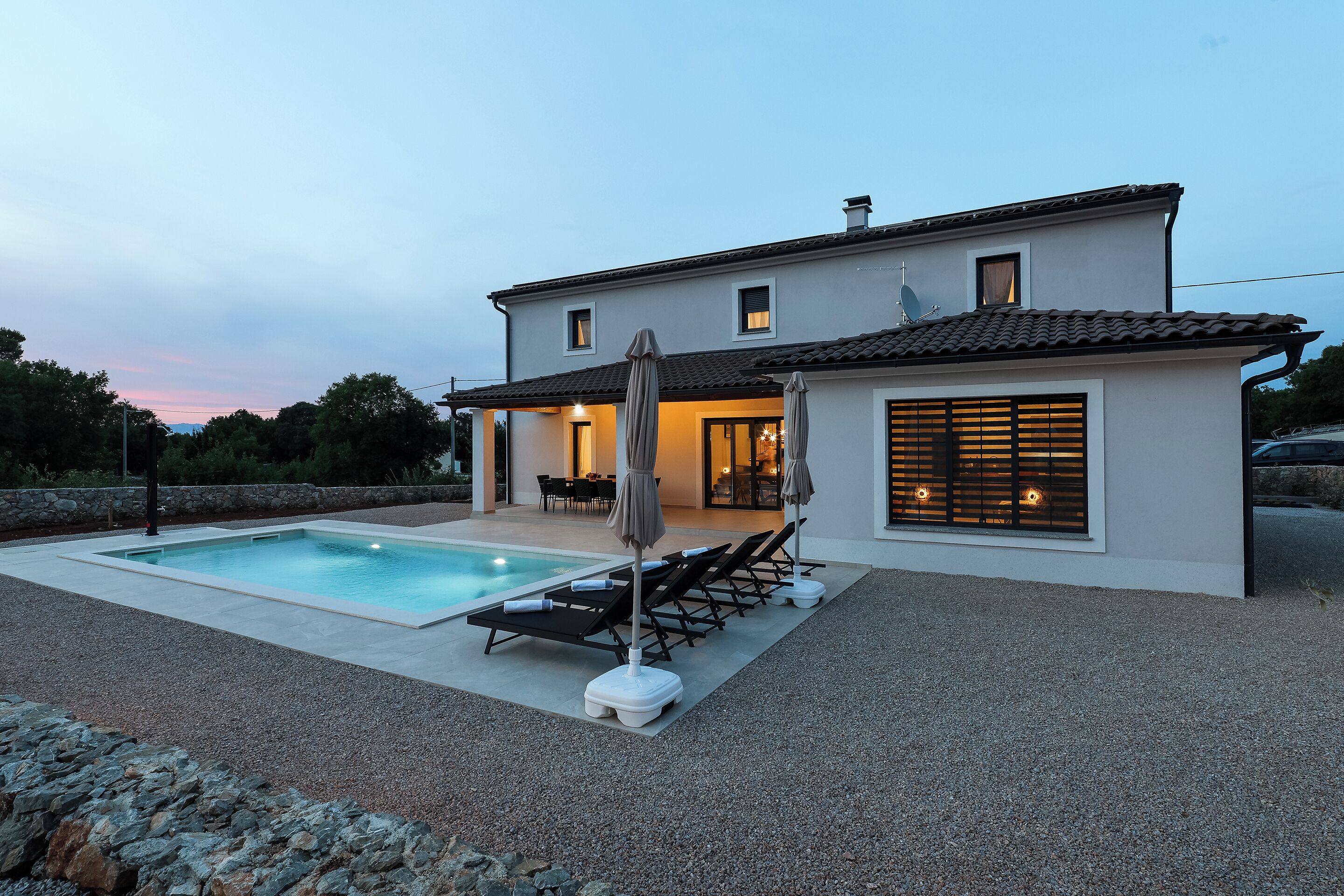 Ein zweistöckiges Haus mit Swimmingpool, Sitzgelegenheiten im Freien und einer überdachten Terrasse.