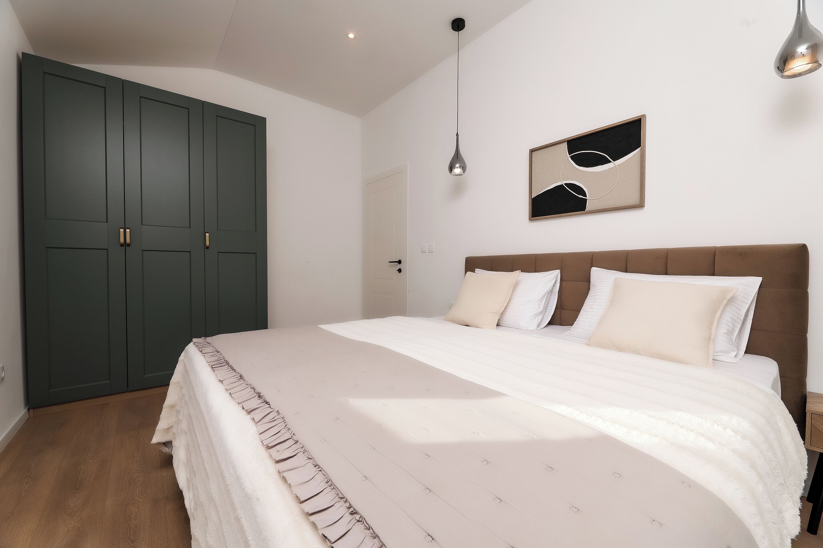 Une chambre à coucher avec un grand lit, une armoire et un luminaire suspendu.