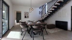 Un comedor moderno con una mesa redonda, sillas y una escalera.