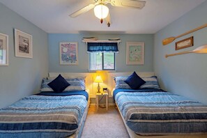 A bedroom with two beds, a ceiling fan, a window with a view, and wall-mounted artwork. - Starfish Haven|Lake View|Pool| Boat Ramp| Sleeps6 (Lake Ozark)