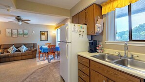 A compact living space with a kitchenette, a dining area, and a sofa with decorative pillows. - Starfish Haven|Lake View|Pool| Boat Ramp| Sleeps6 (Lake Ozark)