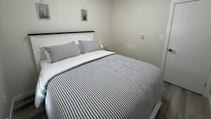 A bedroom with a bed, a bedside table, a nightstand, and a door. - Superb and spacious 2-bedroom apartment in peaceful Saskatoon neighborhood (Saskatoon)