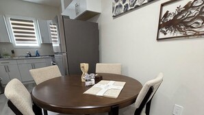 A dining area with a round table, four chairs, a kitchen in the background, and artwork on the wall. - Superb and spacious 2-bedroom apartment in peaceful Saskatoon neighborhood (Saskatoon)