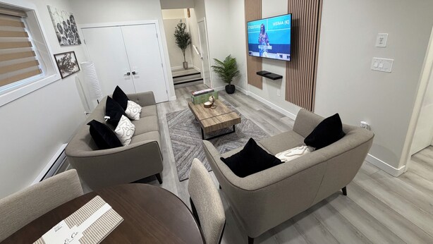 A modern living room with a sofa, armchairs, a coffee table, and a flat-screen TV mounted on the wall. - Superb and spacious 2-bedroom apartment in peaceful Saskatoon neighborhood (Saskatoon)