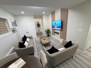A modern living room with a sofa, armchairs, a coffee table, and a flat-screen TV mounted on the wall. - Superb and spacious 2-bedroom apartment in peaceful Saskatoon neighborhood (Saskatoon)