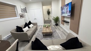 A modern living room with a sofa set, a coffee table, and a flat-screen TV mounted on the wall. - Superb and spacious 2-bedroom apartment in peaceful Saskatoon neighborhood (Saskatoon)
