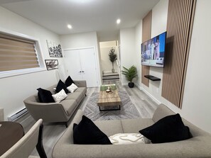 Ein modernes Wohnzimmer mit einer Sofagarnitur, einem Couchtisch und einem flachbildfernseher an der Wand.