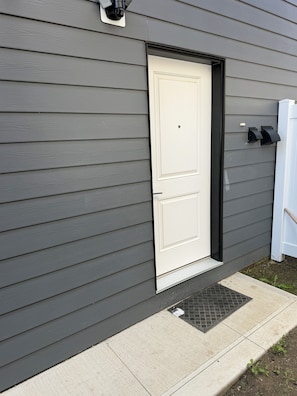 A house with a white door, grey siding, and a small porch with a step. - Superb and spacious 2-bedroom apartment in peaceful Saskatoon neighborhood (Saskatoon)