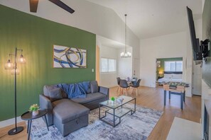 A modern living room with a sectional sofa, a glass coffee table, and a dining area with a table and chairs. - N Scottsdale Oasis Pool Balcony Parking WD WiFi (Scottsdale)