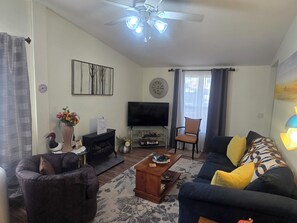 Un salon comprenant un canapé, un fauteuil, une table basse, un téléviseur et des objets de décoration.