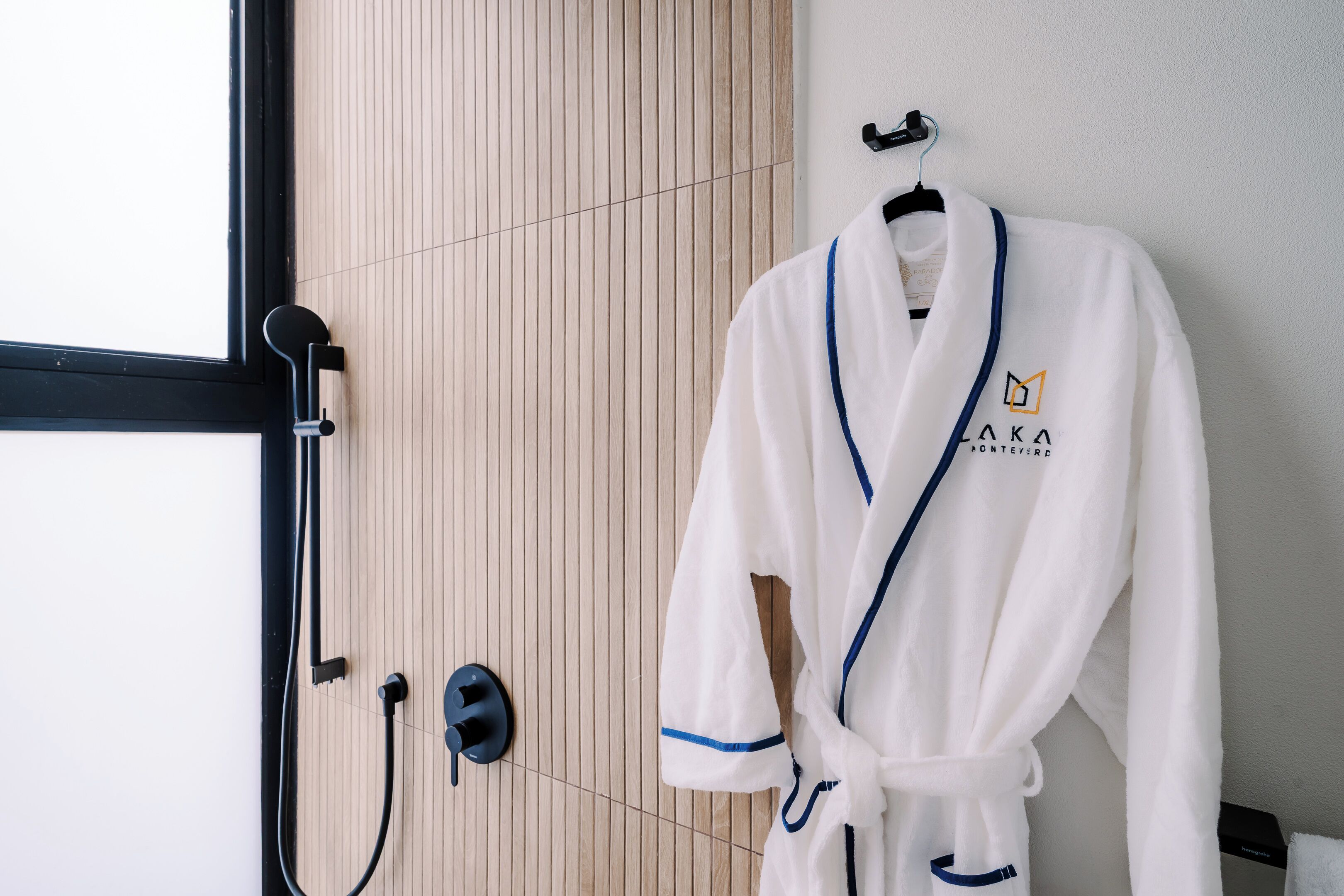 A white bathrobe with a blue trim and logo hanging on a hook.