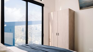 Un dormitorio con un ventanal grande, una cama y un armario.