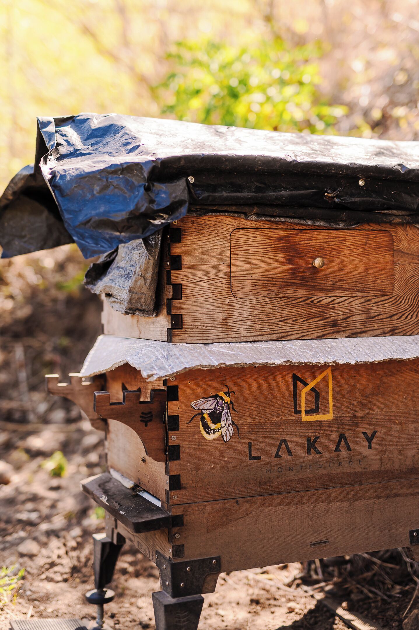 Un colmenar de madera con la etiqueta 'LAKAY' y una ilustración de una abeja.