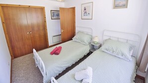 Een slaapkamer met twee eenpersoonsbedden, houten kasten, een plafondlamp en ingelijste foto's aan de muur.