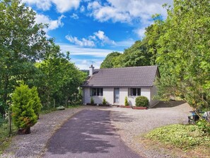 Ein Bungalow mit Kiesweg, umgeben von Bäumen und Grünpflanzen.