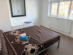 A bedroom with a bed, a window, a radiator, and a mirror. - Spacious 3BR Family Home with Parking (Southampton)