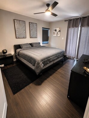 A bedroom with a bed, a desk, a globe, and a ceiling fan.