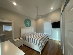 A bedroom with a bed, nightstands, a dresser, a ceiling fan, and a TV mounted on the wall. - On the Intracoastal Waterway with a dock. Bring your boat, minutes to the beach (Oak Island)