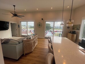 A spacious living area with a large window, a ceiling fan, and a dining area with a view of the outside. - On the Intracoastal Waterway with a dock. Bring your boat, minutes to the beach (Oak Island)