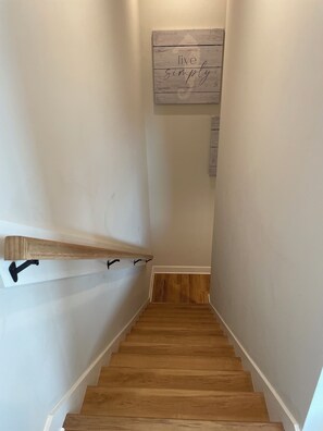 A wooden staircase with a handrail and a wall-mounted sign that reads 'live simply.' - On the Intracoastal Waterway with a dock. Bring your boat, minutes to the beach (Oak Island)