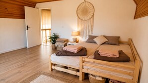 Ein Bett mit Holzkopfende, ein Nachttisch, eine Lampe, ein Traumfänger und eine Pflanze.
