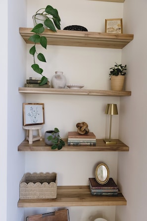 A wooden shelf with decorative items, a framed picture, and a lamp. - The Vella | Private Modern Carriage House Near Shuswap Lake (Tappen)