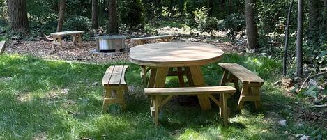 A picnic table surrounded by grass and trees in a forest setting.