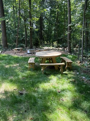 Una mesa de picnic rodeada de césped y árboles en un entorno forestal.