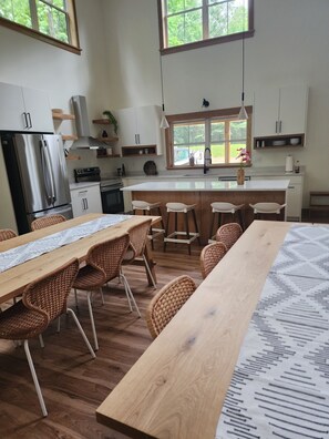 A modern kitchen with a central island, wooden chairs, and a dining table.