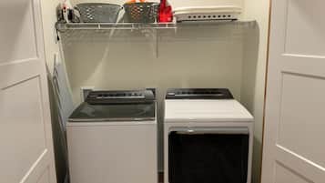 Une buanderie équipée de deux sèche-linge et d’une étagère placée au-dessus.