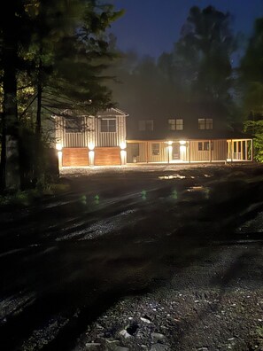 Un bâtiment doté d’un porche et de nombreuses fenêtres, entouré d’arbres.