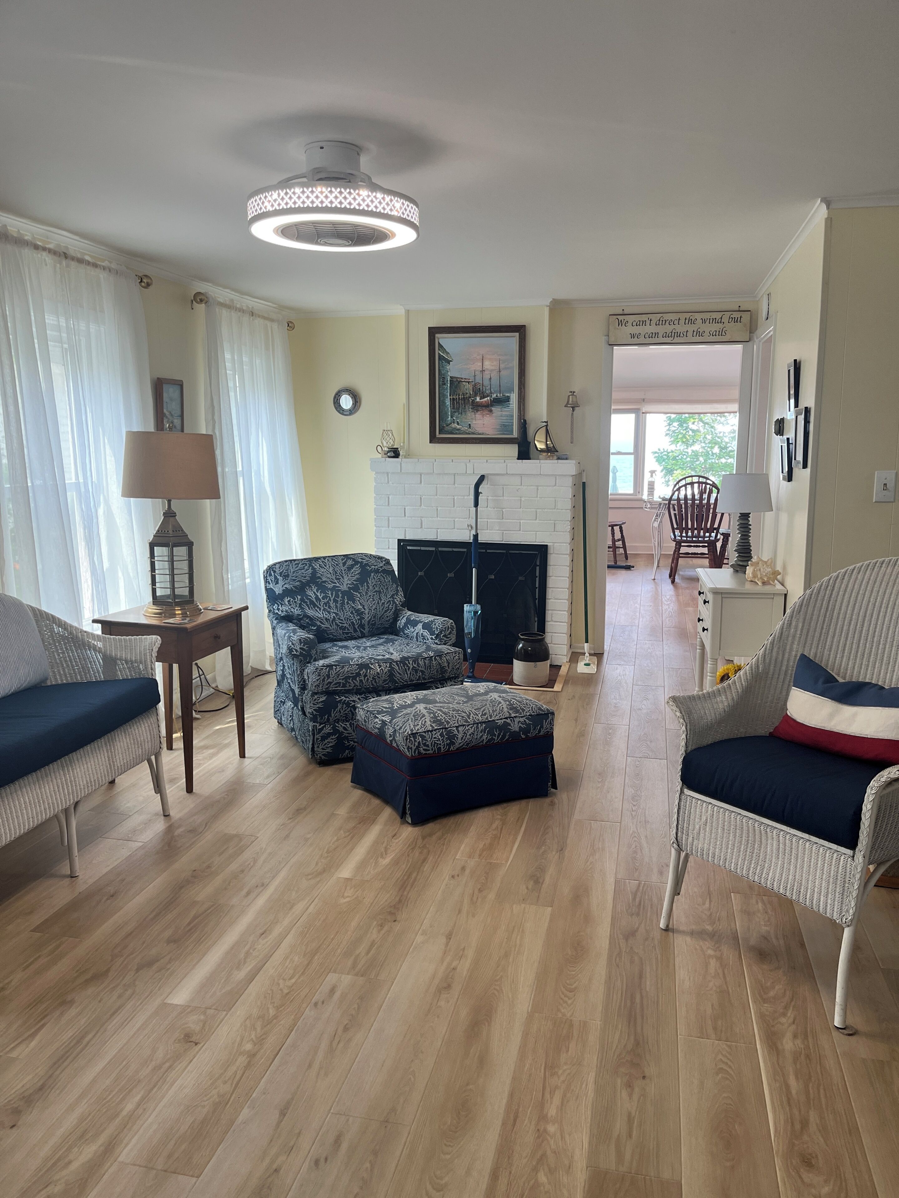 Ein Wohnzimmer mit Rattanmöbeln, einem Kamin und Blick ins Freie.