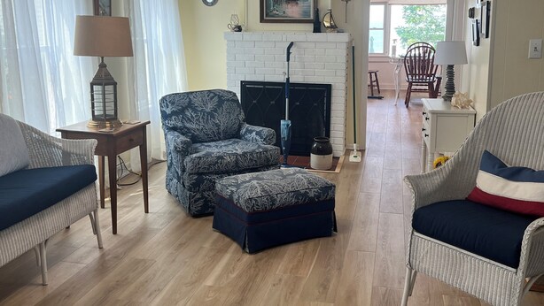 Sala de estar com móveis de vime, lareira e vista para o exterior.