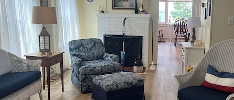 Una sala de estar con muebles de mimbre, chimenea y vistas al exterior.