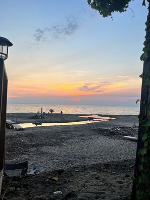 Ein Strand bei Sonnenuntergang, eine Mole und einige Personen.