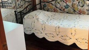 Quarto com cama, piso de madeira, espelho e janela com cortinas.