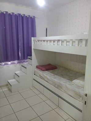 A bunk bed room with a purple curtain, a white wall, and a tiled floor. - Well-located apartment near beaches, shopping, etc. (Vila Velha)
