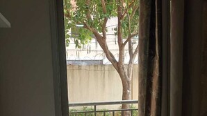 A room with a sliding glass door leading to an outdoor balcony with a metal railing and a tree. - Well-located apartment near beaches, shopping, etc. (Vila Velha)