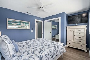 A bedroom with a bed, a dresser, a ceiling fan, a TV, and a door leading to another room. - Intracoastal Waterfront Home | Private Pool, Boat Dock, Screened Lanai, Sleeps 6 (Palm Coast)