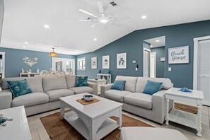 A living room with two sofas, a coffee table, a side table, a ceiling fan, and wall art. - Fall Deals + Snowbird Rates | Coastal Stay With Water Views (Palm Coast)